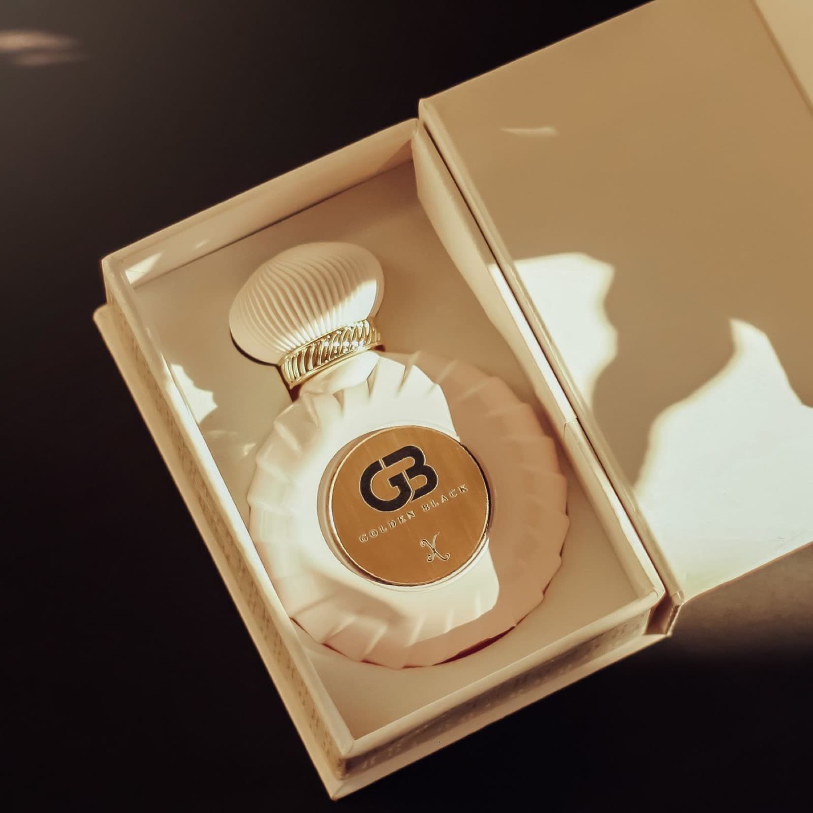 An open rigid box with a fitted interior holding a perfume bottle